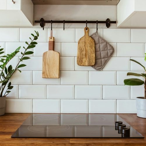 Hanging kitchen with white tiles wall and wood tabletop.Green plant on kitchen background