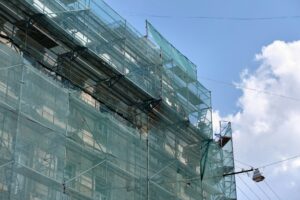 Building facade under renovation works with construction scaffolding frame